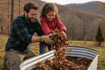 A father in a plaid shirt and work gloves and a young girl in a red jacket add dry fallen leaves to a metal raised garden bed, with bare trees and rolling hills behind them
