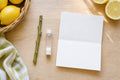 Lemon tree cutting rooting kit flat-lay: a bare leafless lemon cutting, a small vial of rooting powder and an instruction sheet on a wooden table