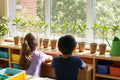 Classroom windowsill lined with potted orange tree cuttings and two students